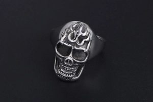 Detailed view of matte silver titanium skull ring with flame tribal engravings