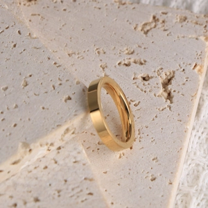 Vue macro d'une bague dorée polie minimaliste avec un profil carré sur pierre