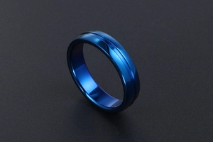 Détail macro d'une bague minimaliste en acier bleu foncé avec rainure sur fond noir