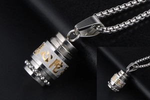 Macro detail of silver and gold spinning cylinder pendant with engraved Buddhist mantra