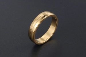 Détail d'une bague dorée polie minimaliste avec rainure sur un fond noir texturé