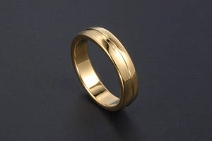 Gros plan d'une bague dorée avec rainure horizontale centrale sur un socle gris mat