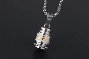 Macro detail of stainless steel Buddhist cylinder pendant with golden engraved sutra text