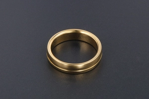 Vue détaillée d'une bague dorée avec une rainure centrale minimaliste sur une surface sombre