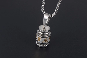 Close-up of Buddhist cylinder pendant with golden scriptures and silver box chain
