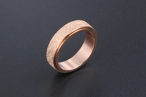 Macro detail of rose gold rotating ring featuring a frosted finish and smooth inner band