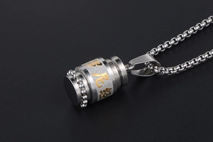 Macro shot of silver cylinder mantra pendant necklace with golden scripture engraving