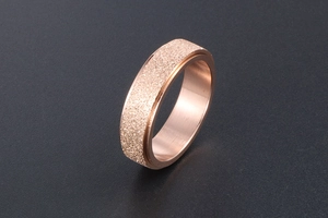 Detail view of rose gold spinning ring with frosted texture and polished edges