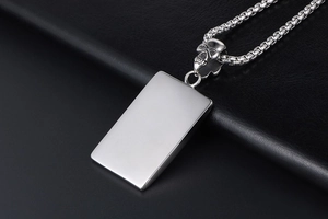 Détail du pendentif rectangulaire en acier argenté avec bélière tête de mort et chaîne billes
