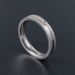 Frosted stainless steel couple ring with embedded cubic zirconia on a gray surface
