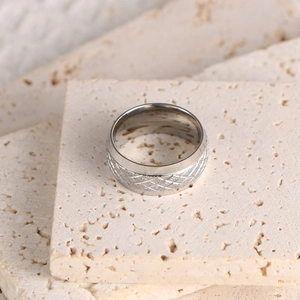 Vue macro de la texture losange mate sur une bague en titane posée sur pierre