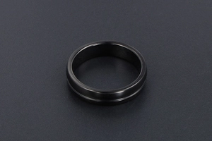 Détail d'une bague en acier inoxydable noir avec une rainure décorative centrale élégante