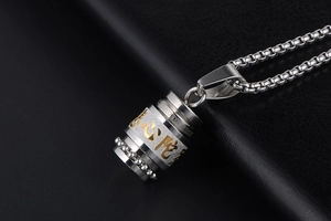 Close-up of a silver cylinder spinning pendant necklace with gold scripture engraving