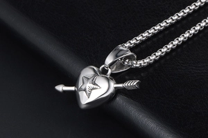 Macro view of polished heart pendant with star and arrow on silver box chain