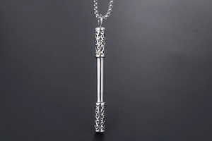 Macro shot of silver Sun Wukong staff pendant with hollow cloud carvings on steel