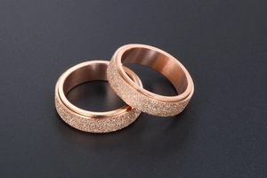 Close-up of rose gold spinning rings with matte frosted finish and brushed inner metal band