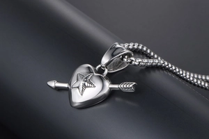 Macro side view of polished silver heart and arrow pendant on industrial box chain