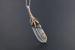 Macro detail of antique silver eagle claw feather pendant with intricate textures
