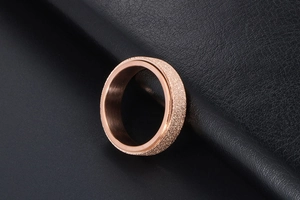 Close-up of rose gold spinner ring featuring a frosted surface and polished inner band
