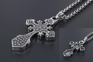 Macro detail of vintage gothic cross necklace showing embossed patterns and matte back