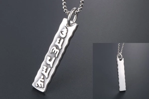 Detail of silver mantra pendant with wavy edges and embossed religious symbols