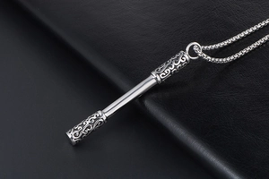Close-up of Ruyi Jingu Bang pendant with intricate carvings on a black leather surface