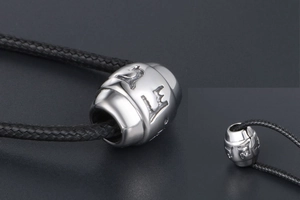 Detailed close-up of a titanium steel cylinder charm with embossed Sanskrit engraving