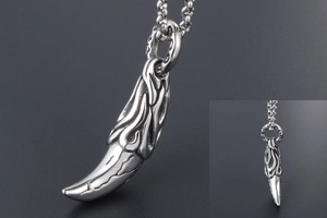 Macro detail of men's punk wolf fang pendant with flame relief and silver metal texture