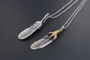 Detail shot of vintage silver feather pendants with golden eagle claw and ethnic motifs