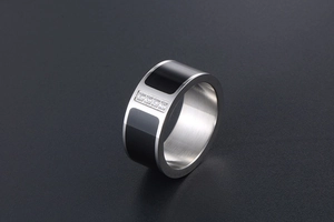 Detail of wide titanium steel band ring with black enamel and four central diamonds