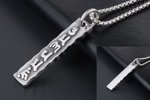 Macro detail of Buddhist mantra relief on a vintage titanium steel bar pendant
