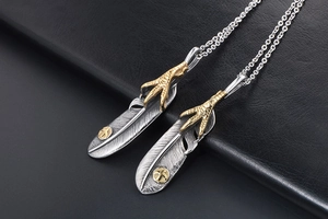 Detailed macro shot of vintage eagle claw and feather pendant on black leather