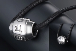 Detailed close-up of polished silver cylinder bead with engraved religious symbols