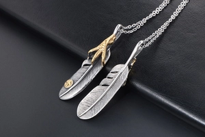 Detailed macro of vintage silver feather pendants with gold accents and eagle claw detail