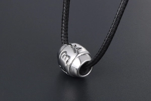 Macro shot of silver titanium steel barrel bead with engraved Six-Word Mantra symbols