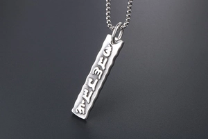 Macro detail of silver titanium steel bar pendant featuring engraved six-syllable mantra