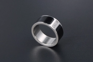 Macro detail of men's brushed titanium ring with black enamel and three inset zircons