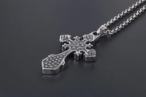Detailed close-up of a vintage gothic steel cross pendant with black textured finish
