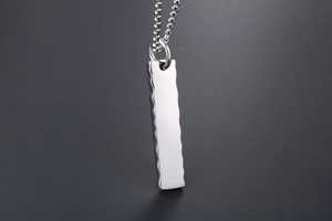 Macro detail of polished stainless steel rectangular pendant with wavy edge texture