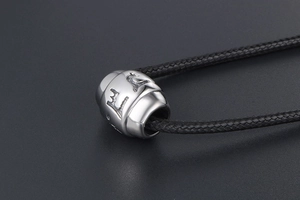 Macro shot of silver stainless steel bead with engraved Six-Syllable Mantra characters