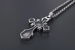 Macro detail of gothic silver cross pendant with vintage floral engravings and chain