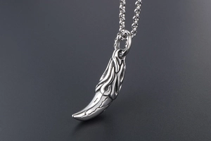 Macro detail of men's titanium wolf tooth pendant necklace with vintage flame carvings
