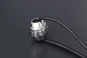 Macro shot of silver titanium cylinder pendant with engraved Buddhist mantra and woven cord
