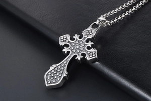 Detailed view of gothic cross pendant with intricate embossed texture on leather surface