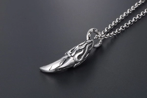 Detailed view of vintage wolf tooth pendant with flame carvings and crackle finish