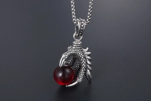 Detailed close-up of a dragon claw pendant holding a translucent red gemstone ball
