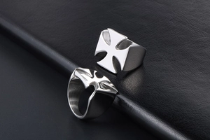 Detailed view of silver Maltese cross rings on a textured black leather background