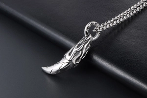 Macro shot of vintage wolf tooth pendant with flame relief and smoked steel finish