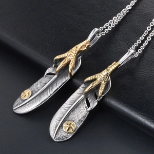 Vintage silver feather pendant with golden eagle claw on a detailed cross chain necklace