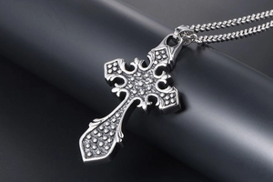 Macro shot of gothic silver cross pendant with intricate dot texture and wheat chain